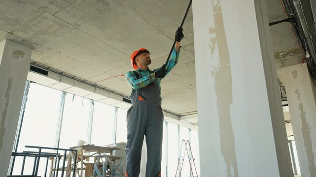 Construction worker priming walls in a building under construction