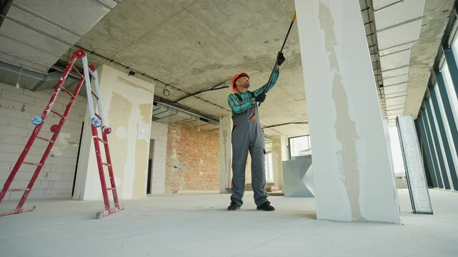 Construction worker priming walls in a building under construction