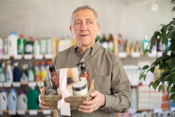 Mature man examines product and doubts choice, chooses shower cosmetic kit present household...