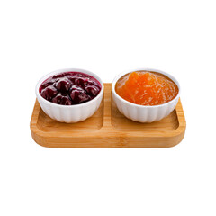 Two round white ceramic bowls with cherry and apricot jams on a wooden tray, ideal for gourmet...