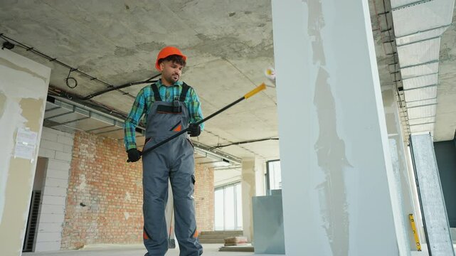 Construction worker priming walls in building renovation