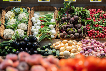 Baskets of fresh vegetables: potatoes, radishes, tomatoes and cabbage on the supermarket counter....