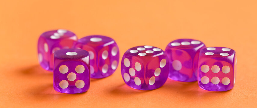 Purple dices on orange background, closeup