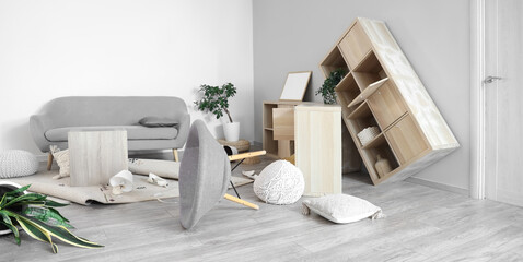 Interior of messy living room with overturned furniture after earthquake