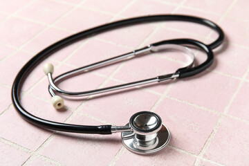 Modern stethoscope on pink background