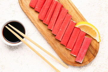 Wooden board with tasty crab sticks and sauce on light background, closeup © Pixel-Shot