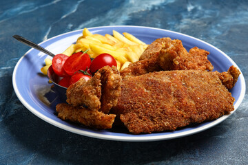 Plate of tasty fried codfish on blue background