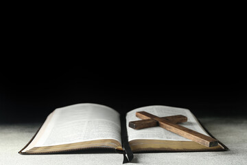 Holy Bible with wooden cross on dark background