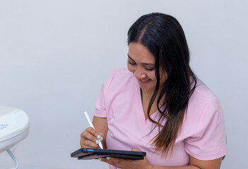 Female nurse smiling while using stylus on tablet