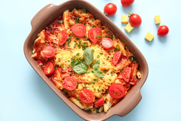 Baking dish of pasta with tomato sauce and cheese on blue background