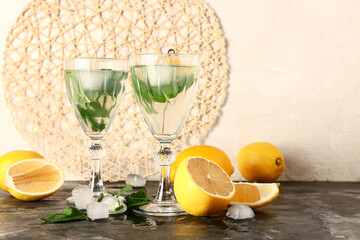 Glasses of cold mojito and lemons on dark table