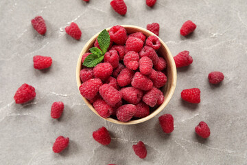 Bowl with fresh raspberry and mint on grey background, closeup