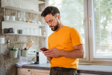 cheerful adult man use mobile phone in the kitchen