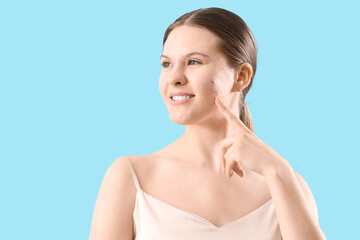 Teenage girl with acne problem on blue background, closeup