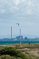 kitesurf in marine seascape with chimneys in the background and a windsurfer Porto Torres Sardinia,...