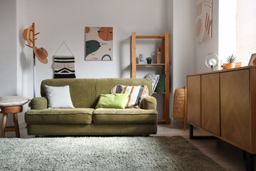 Green sofa with cushions in interior of cozy living room