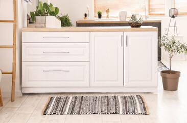 Interior of light kitchen with white counters and striped carpet