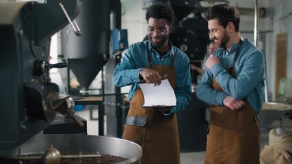Two multiethnic happy African Caucasian men talking smiling coffee factory inspection checklist quality roaster teamwork supervision coworkers espresso machinery roasting aroma beverage manufacturing - Powered by Adobe