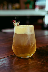 A refreshing cocktail with foam, beautifully garnished and ready to be enjoyed.