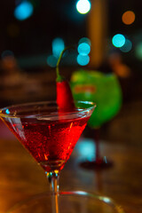 A beautifully illuminated red cocktail with chili garnish, perfect for any occasion.