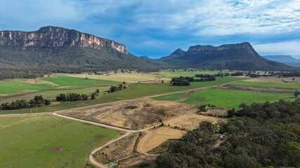 Drone aerial photograph of lush agricultural farmland and vegetation along the cliff face in Capertee Valley in Wollemi National Park in the Central Tablelands of NSW, Australia.