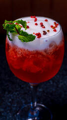 This vibrant cocktail is garnished with mint and pink peppercorns, perfect for a celebration.