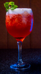 A stunning red cocktail with mint garnish in a tall elegant glass, ready to enjoy.