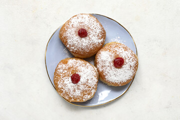 Plate with sweet donuts for Hanukkah celebration on light background