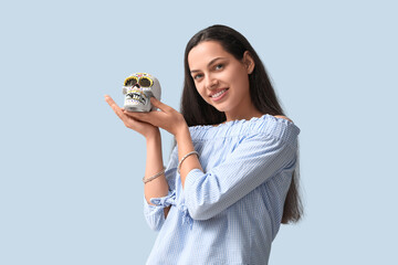 Happy young woman with painted human skull on blue background