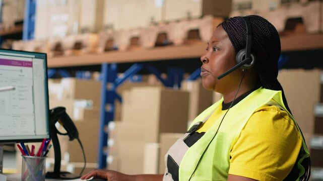 Black female customer support clerk speaks with clients about shipment details, helping with wrong address mix up on the help line. Woman resolves order, confirm airway bill numbers. Camera B.