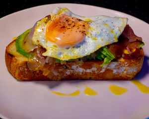This open-faced toast is topped with avocado, fried egg, and is ready to eat.