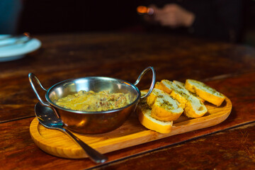 Creamy dip served with toasted garlic bread on a wooden platter, perfect for sharing.