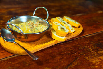 Creamy dip served with toasted garlic bread on a wooden board.