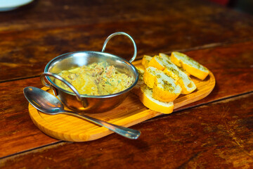 Creamy dip with toasted garlic bread is a perfect appetizer served on a wooden tray.