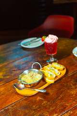 Delectable meal display featuring a vibrant cocktail, bread slices, and a delicious dip.