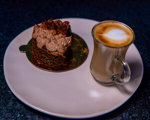 Chocolate cake slice with a latte on a plate, a perfect breakfast treat.