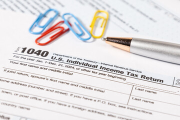 A U.S. tax document Form 1040 is placed neatly on a desk alongside a pen, representing the annual...