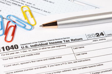 A U.S. tax document Form 1040 is placed neatly on a desk alongside a pen, representing the annual...