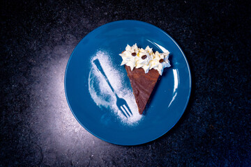 A slice of rich chocolate cake with whipped cream and coffee beans on a blue plate.