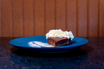 Delicious chocolate dessert slice with whipped cream and coffee beans on a blue plate.