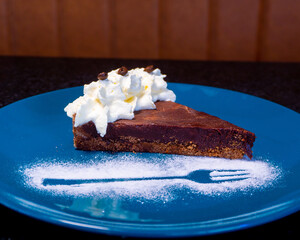 A mouthwatering slice of chocolate cake with whipped cream is beautifully presented on a blue plate.