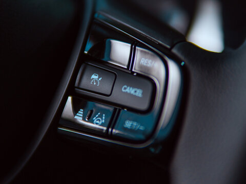 Car steering wheel controls with cruise control and lane assist features in a modern vehicle.