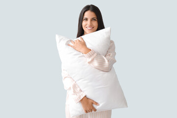Fototapeta premium Beautiful woman with soft pillow on light background