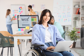 Female designer in wheelchair working with laptop at office