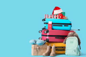 Suitcases with winter and travel accessories on blue background