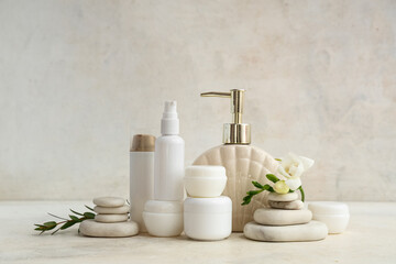 Composition with different cosmetic products, spa stones and flower on light background