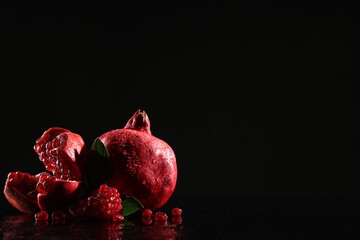 Pieces of ripe tasty pomegranate on black background