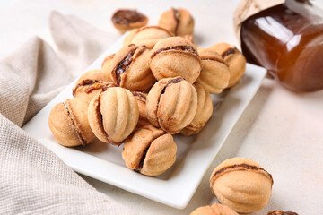 Plate with sweet walnut shaped cookies with boiled condensed milk on white background, closeup