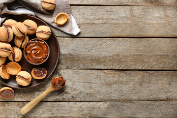 Plate with sweet walnut shaped cookies with boiled condensed milk on wooden background