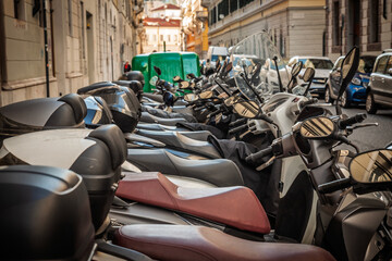 Parked scooters tightly fill a narrow one way street in Trieste, Italy. Polished mirrors, leather...